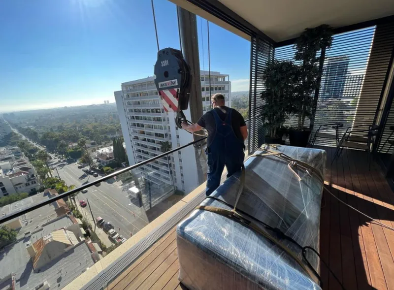 Crane lift delivering furniture to a high-rise balcony